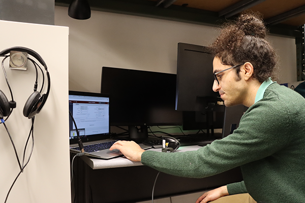 Labib works at his desk, surrounded by computer monitors.